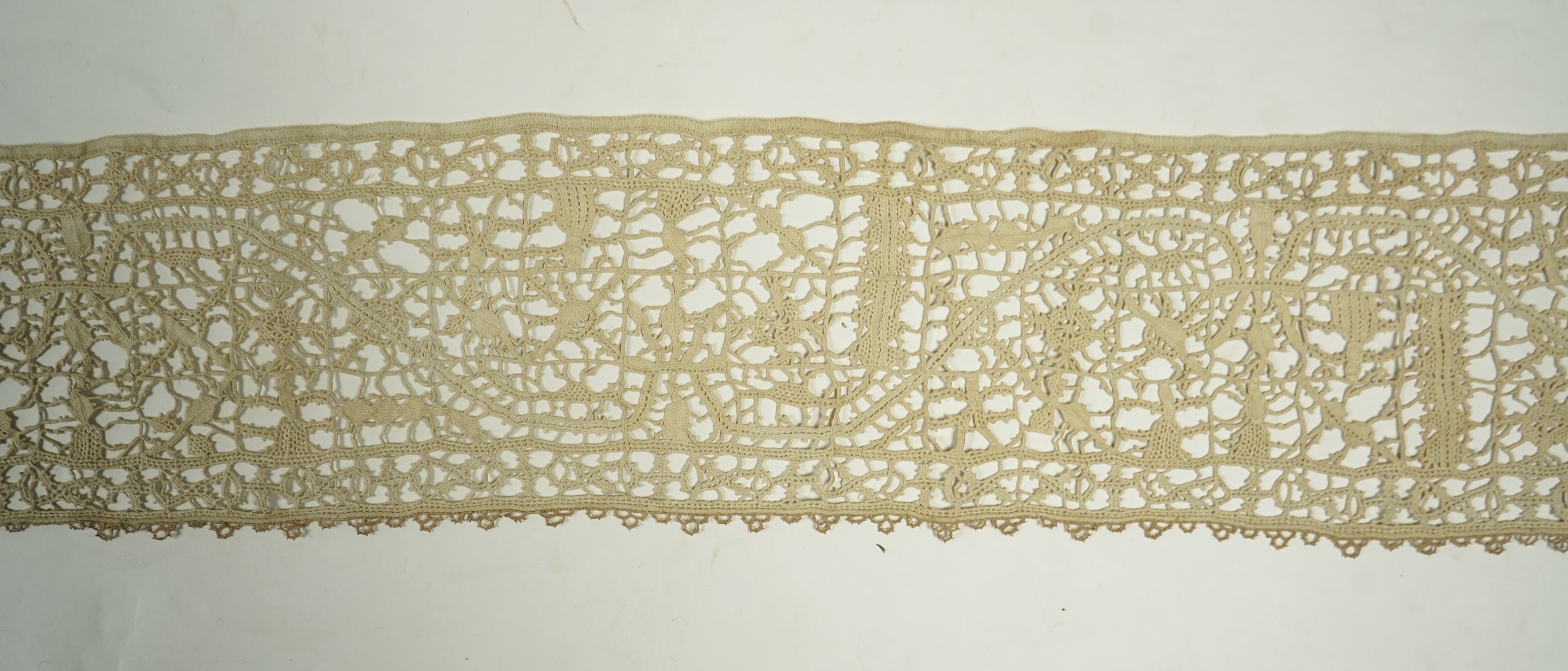 A length of late 16th early 17th century Venetian Reticella needle lace. Possibly cut from a wider panel or the edge to an Ecclesiastical robe or a furnishing lace. Designed with figures, worked in button hole stitch. 17